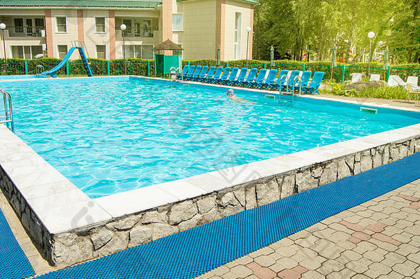 室外游泳池位于休闲区境内的一家豪华度假酒店内，是夏日田园诗般度假的概念。阳光明媚的一天。