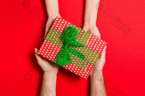 在彩色背景上，男女手持礼物的俯视图。女人和男人送和接受礼物。度假时间概念与公司