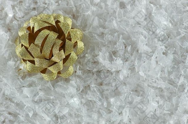白色雪地上包裹圣诞礼物的金色丝带蝴蝶结。俯视图