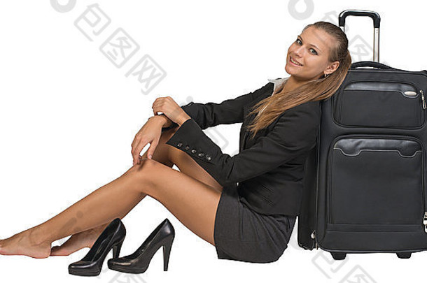 脱鞋的女商人坐在前视行李箱旁边