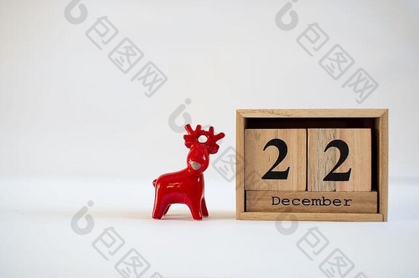 立方体木制日历，显示12月22日的日期，白色背景上有陶瓷驯鹿雕像。降临节日历，圣诞节背景