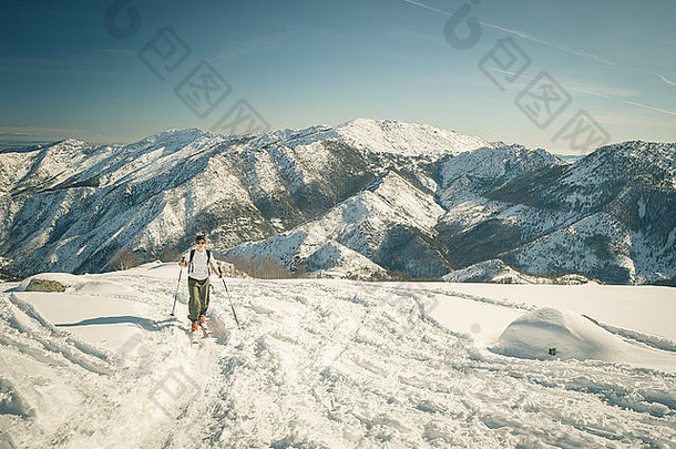 在意大利阿尔卑斯山，旅游滑雪者在明亮的阳光下，在雪景中爬山。交叉到复古风格