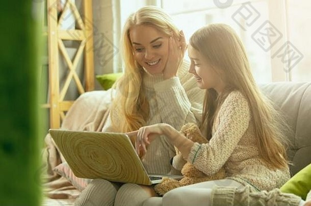 玩得开心。幸福的家庭。母亲和女儿一起在家度过时光。看电影，使用笔记本电脑，大笑。<strong>母亲节</strong>，庆祝<strong>活动</strong>，周末，节日，童年的概念。