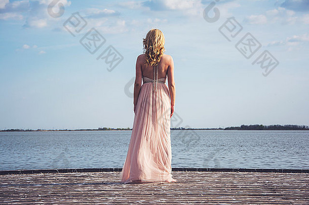 回来potrait美丽的金发碧眼的卷曲的女人穿晚上桃子颜色礼服湖时尚迷人的衣服链