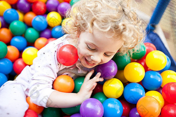 一个年轻的金发女孩正在玩彩色塑料球