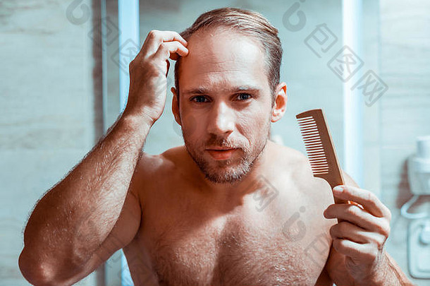 勤劳的短发男人用小刷子纠正他的发型