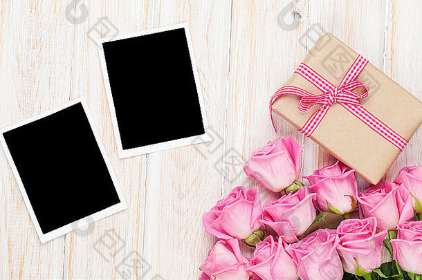 粉色<strong>玫瑰</strong>和情人节礼物盒，木质桌子上方的两个空白相框。具有空间的俯视图