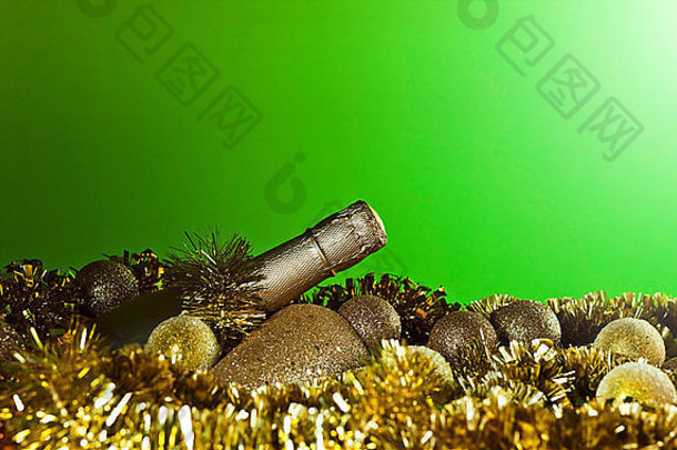 绿色背景上的香槟酒瓶和金色圣诞装饰