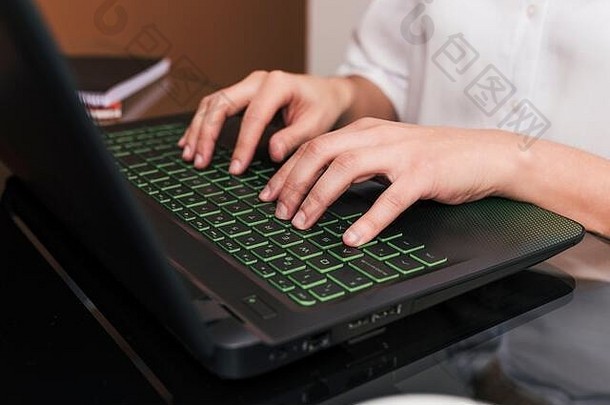 女商人在家办公桌上使用笔记本电脑的特写镜头。在家工作的概念。