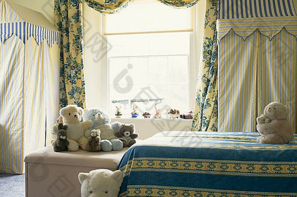 儿童卧室的蓝色和黄色花朵窗帘和条纹床单，以及泰迪熊和条纹织物<strong>储藏柜</strong>