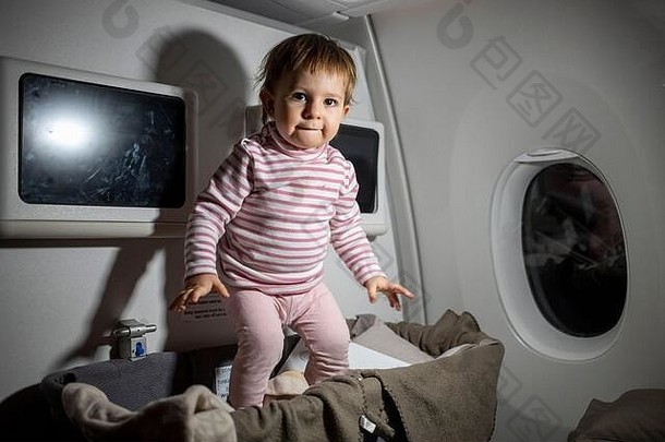 在<strong>飞机</strong>上违反安全规则。危险在飞行中，可爱的蹒跚学步的小孩在婴儿摇篮中跳跃。
