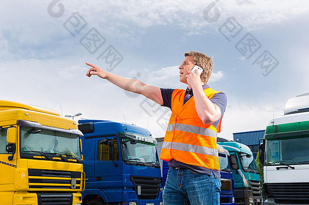 物流-在转运点，自豪的司机或货运人在卡车和拖车前使用<strong>手机</strong>