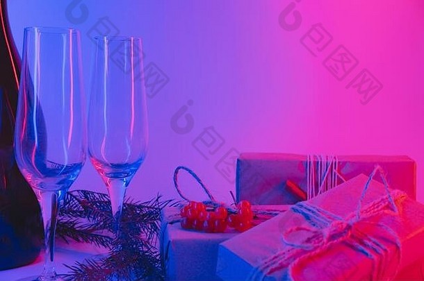 霓虹灯可持续包装的圣诞礼物。新年派对概念：粉色和蓝色背景的礼物、饮料和眼镜