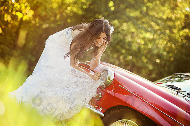 绿色草地上美丽的黑发新娘，带着复古汽车