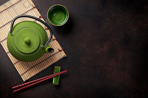石桌上的绿色茶壶和茶杯。具有空间的俯视图