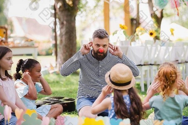 夏天，男人<strong>带</strong>着<strong>小孩</strong>在花园里的地上玩耍。
