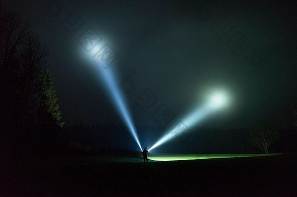 雨雾蒙蒙的夜晚，站在户外用手电筒照明的人。瑞典自然和风景的神秘和抽象照片。