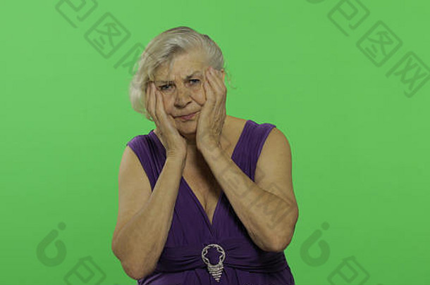 一位老妇人头痛。穿着紫色连衣裙的漂亮老奶奶。放置您的徽标或文字。色度键。绿色屏幕背景。情感概念