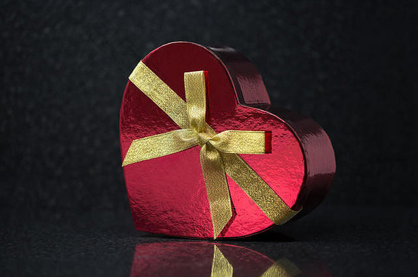 红色心形礼品盒，黄色丝带，代表深色背景中的情人节礼物