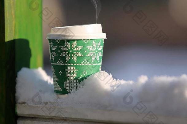 一杯热乎乎的咖啡在冬天的户外风景中为文字留出了空间