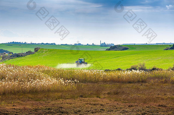 拖拉机在塞浦路斯沼泽附近的大片绿地上喷洒化学物质。