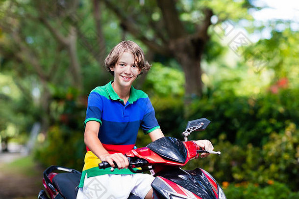 少年骑摩托车。十几岁的男孩在上学的路上骑摩托车玩得很开心。在热带城市骑摩托车的学生。旅游交通