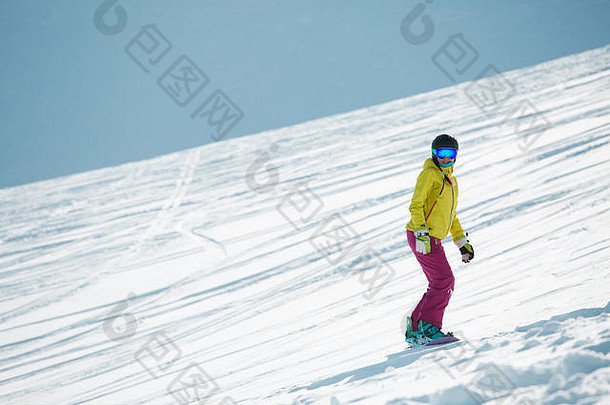 戴着头盔和面具的女运动员，从山坡滑雪
