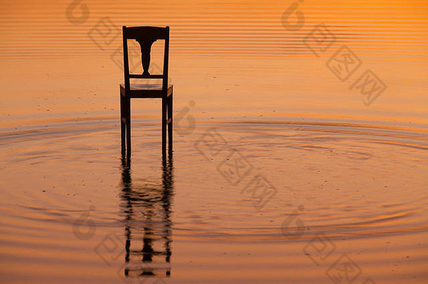 日落时池塘表面的木椅。