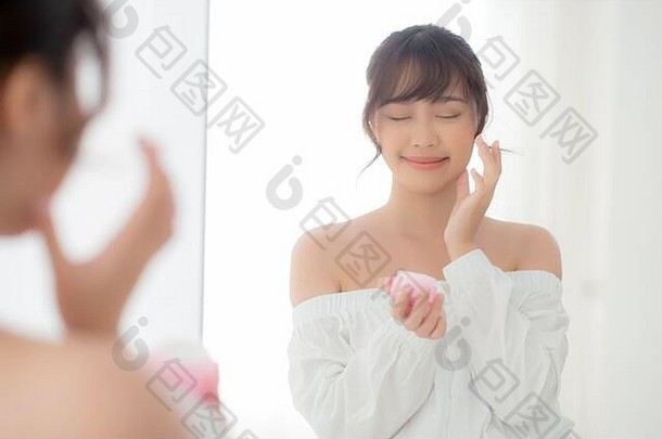 美丽的肖像年轻的亚洲女人应用奶油保湿霜乳液皮肤护理化妆品脸镜子女孩治疗面部healt