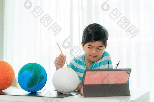 亚洲小<strong>学生</strong>在科学课上画月亮，通过与老师和其他同学的视频会议学习太阳系
