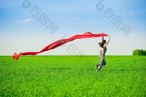 美丽的年轻女子用彩色纸巾在绿色草地上跳跃