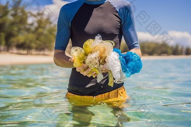 人们从美丽的绿松石海收集包裹。天堂海滩污染。垃圾在沙滩上的溢出问题是由
