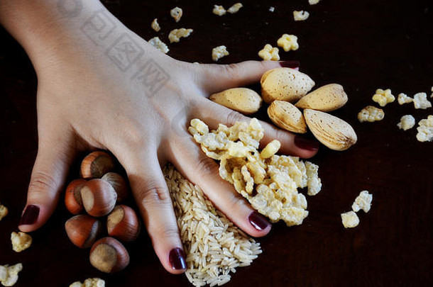 用女人的手放在桌子上的谷物、坚果和谷类食品
