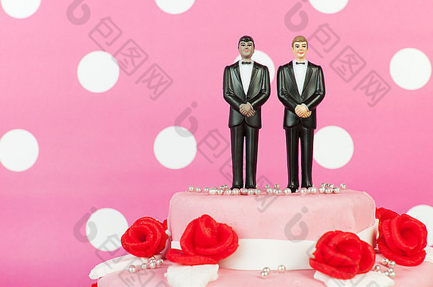 粉色婚礼蛋糕，上面有红玫瑰和夫妇