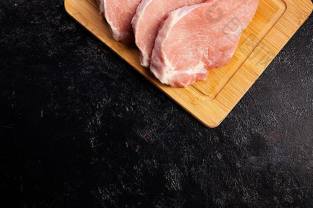 四块新鲜的生牛排肉放在黑胡同的木板上