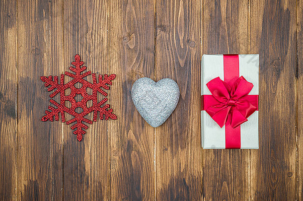 礼品盒在木制背景上用爱心和雪形状包裹丝带