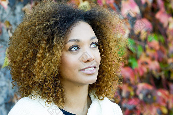 美丽的年轻的非洲美国女人非洲式发型发型绿色眼睛穿白色冬天衣服秋天叶子背景