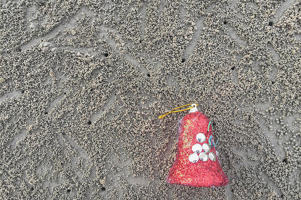 沙滩上装饰的圣诞链、铃铛和丝带。