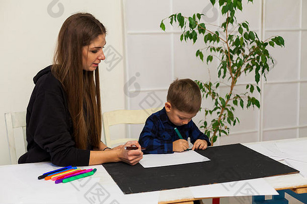 一位妇女教一个小男孩画马克笔