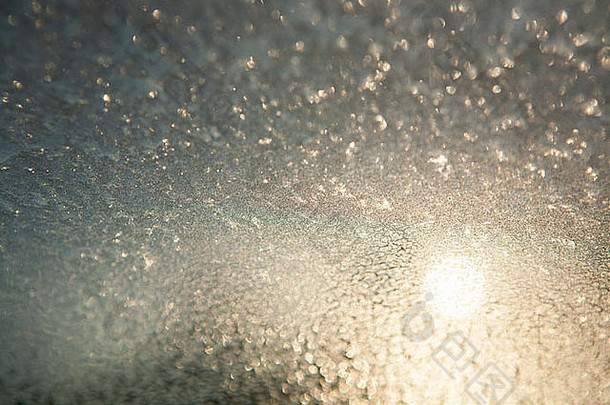 冻结的汽车挡风玻璃正在解冻，冰正在融化