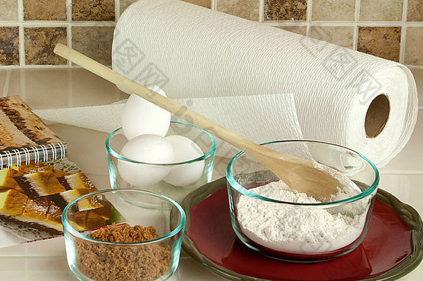 烘焙工具和配料，包括面粉、红糖和鸡蛋，<strong>放</strong>在厨房柜台<strong>上</strong>的玻璃碗里，防止<strong>瓷砖</strong>飞溅