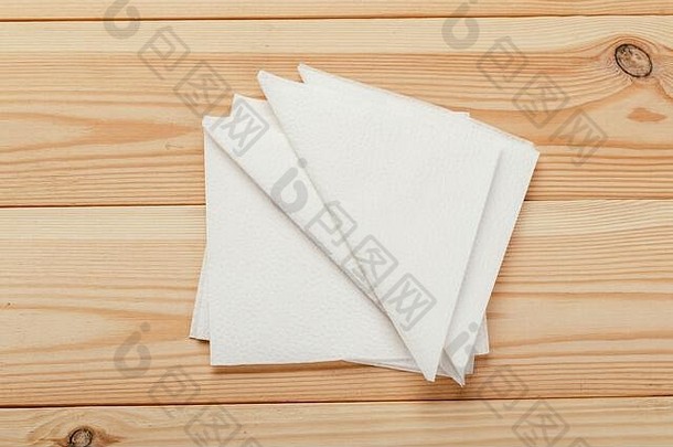 木质桌子背景上的白色餐巾或纸巾。