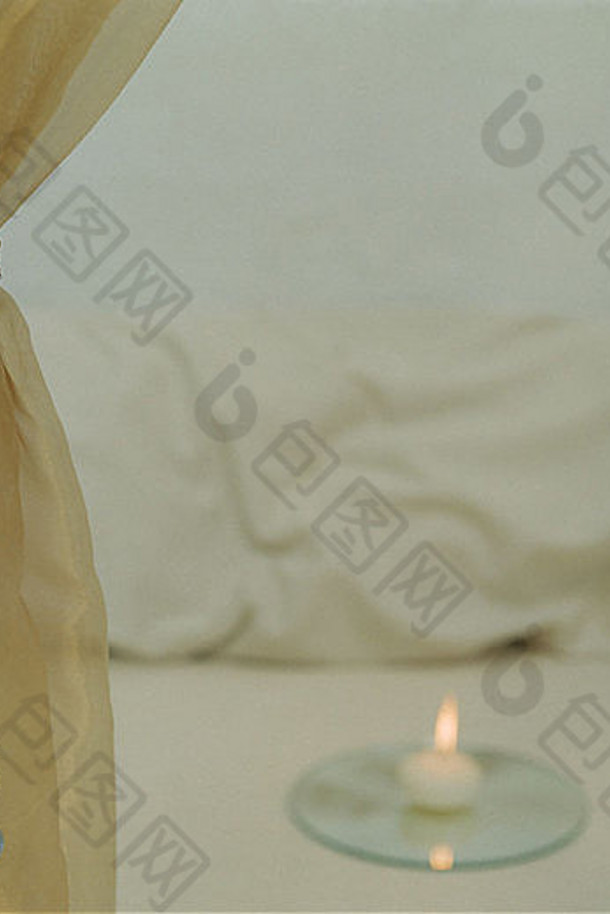 玻璃灯座中点燃的蜡烛旁的青铜百叶窗帘和金属领带的特写镜头