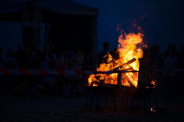 巨大的篝火燃烧着柔和的火焰，四周闪烁着火花。浪漫的夏夜，人们在fe放松和享受宁静