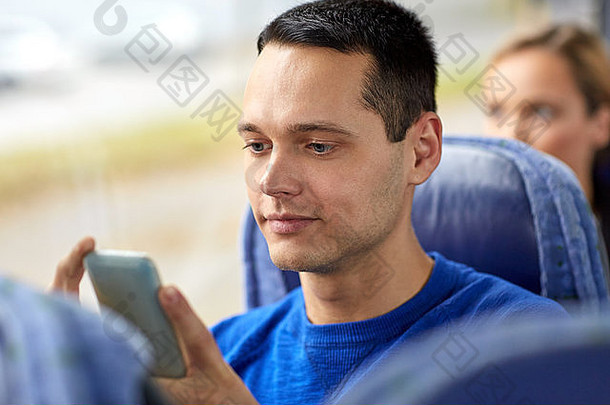 带着智能手机坐在旅游巴士上的快乐男人