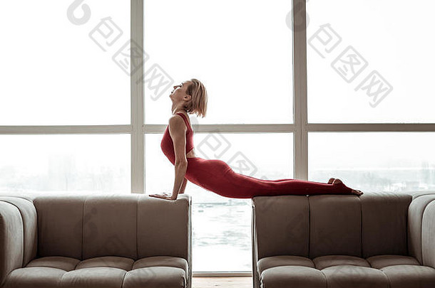 穿着鲜红色服装表演瑜伽的迷人的强壮女人