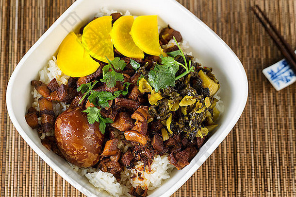 亚洲菜的俯视图，包括切片猪肉、酱油蛋、泡菜、米饭和筷子。