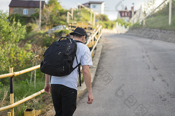 一个背着背包的时髦年轻人独自走在山路上