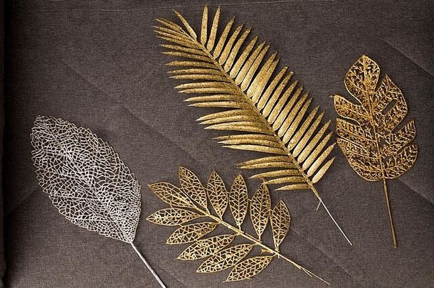灰色织物沙发上的外来植物的金色和银色塑料树枝