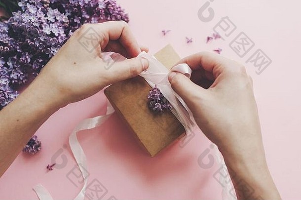 手包装礼物盒子丝带淡紫色花粉红色的纸快乐母亲一天概念时尚的花问候卡紫色的淡紫色花建